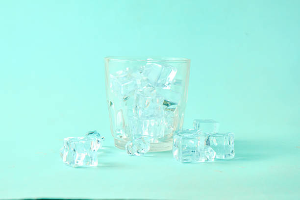Clear glass filled with ice cubes on a soft pastel mint background, with scattered ice cubes creating a clean, minimal still life composition. This image represents freshness, cooling, hydration, and simplicity, ideal for beverage concepts, summer themes, wellness branding, advertising, and modern design mockups with copy space.