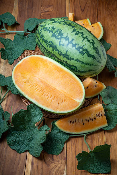 Yellow watermelon with leaf on wooden background. Watermelon seedless tropical fruit on wooden table.
