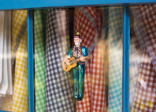 Santa Fe, NM: A shop window retail display of checked kitchen towels and a Willie Nelson Christmas ornament.