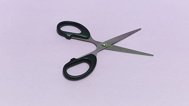 istock Scissors with black handles on purple background for crafting 2253878090