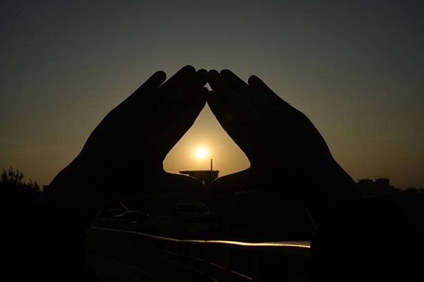 He was posing with both hands, framing the setting sun within the \