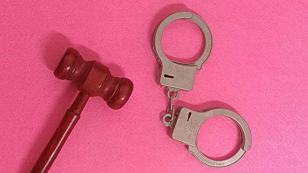 Justice system symbols with gavel and handcuffs on pink background