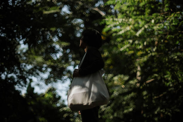 In-Silhouette of a mature woman carrying a reusable tote bag.
