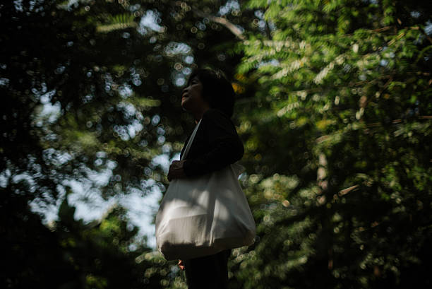 In-Silhouette of a mature woman carrying a reusable tote bag.