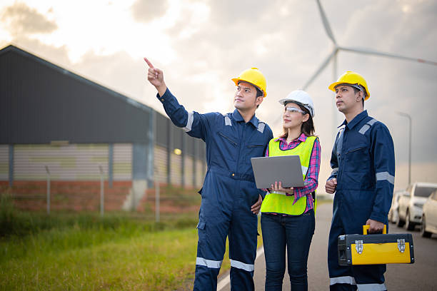 istock Renewable energy maintenance. Engineer using laptop computerchecking system of wind turbine at windmill field farm station. Wind turbine energy storage system. Workers meeting to check around the area 2253887154