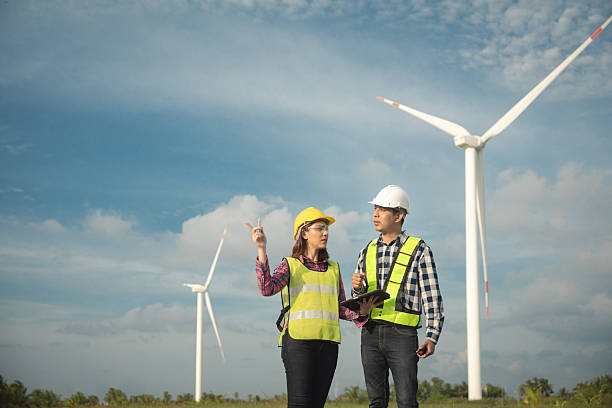 istock Renewable energy maintenance. Engineer using digital tablet checking system of wind turbine at windmill field farm station. Wind turbine energy storage system. Workers meeting to check around the area 2253887197