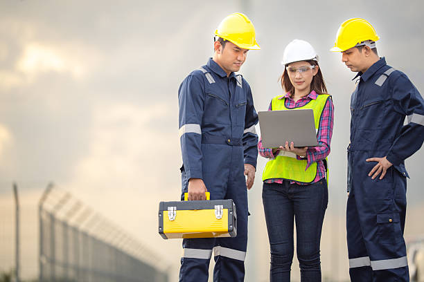 istock Renewable energy maintenance. Engineer using laptop computer checking system of wind turbine at windmill field farm station. Wind turbine energy storage system. Workers meeting to check around the area 2253887200