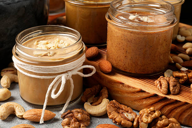 istock Tasty nut butters in jars and raw nuts on table, closeup 2253887591
