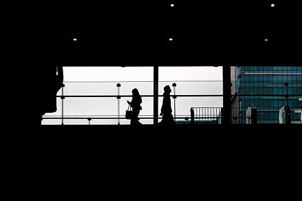 istock Silhouette of two people walking away from each other, on elevated train station platform 2253888050