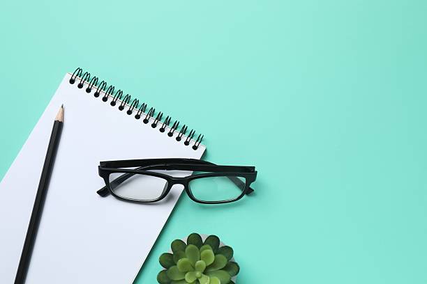 istock Notebook with a pencil, glasses and green plant on color background, space for text 2253892914