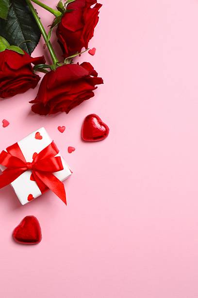 istock Beautiful red roses, gift box and hearts on pink background 2253893685