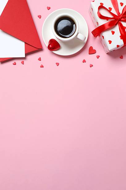 istock Cup of coffee with gift box, paper envelope and hearts on pink background 2253893809