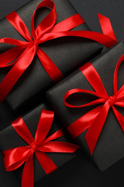 istock Beautiful gift boxes tied with red bows on black background 2253894235