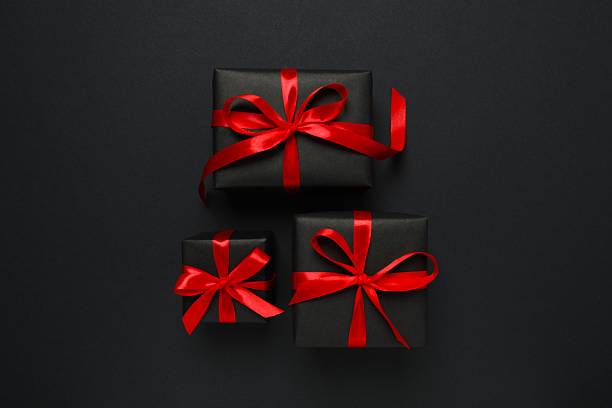 istock Beautiful gift boxes tied with red bows on black background 2253894236