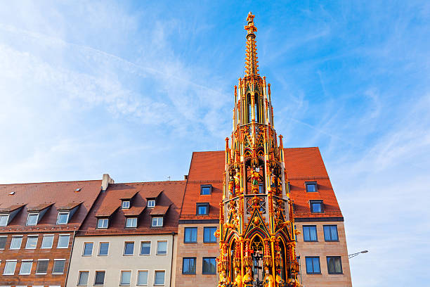 Schoner Brunnen fountain in Nuremberg, Germany, a towering Gothic structure gleaming under a blue sky, situated in city main market square, surrounded by traditional buildings with tiled roofs