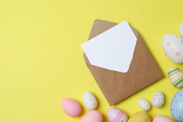 istock Happy Easter. Colorful eggs with paper envelope on yellow background, space for text or advertising 2253894980