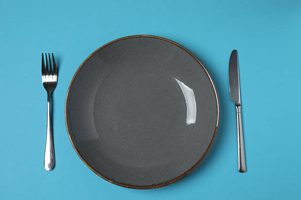 Empty plate and cutlery on colored background, top view