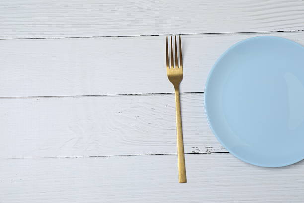 Empty plate and cutlery on colored background, top view