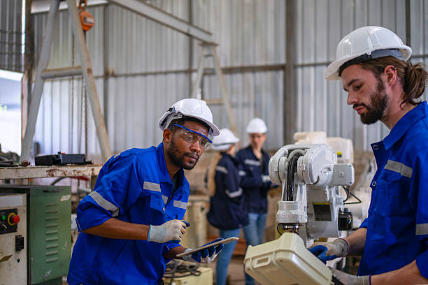 istock Blue collar workers are working at machine shop with welding robot arm. 2253899594