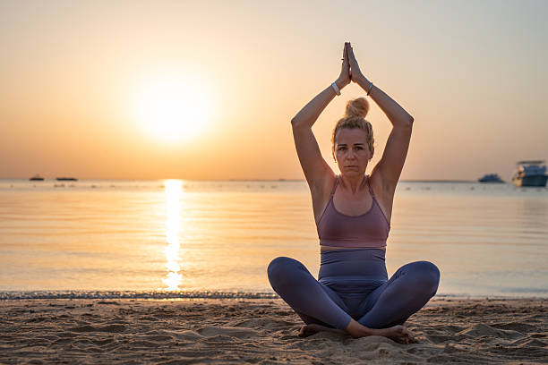 istock Serious female is meditating on beach during golden sunset. 2253902427