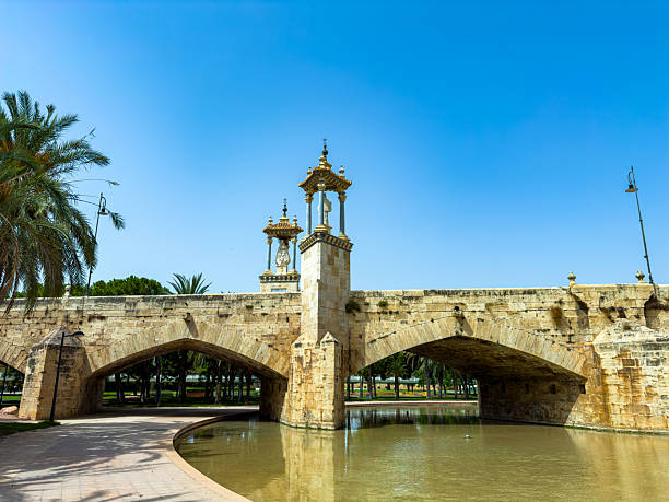 istock Stunning bridge with golden towers under a clear blue sky in a tranquil park setting surrounded by lush greenery 2253903745