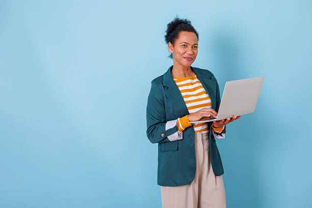 istock Smiling woman holding a laptop, typing, and working remotely. Representing business, technology, and freelance work 2253904228