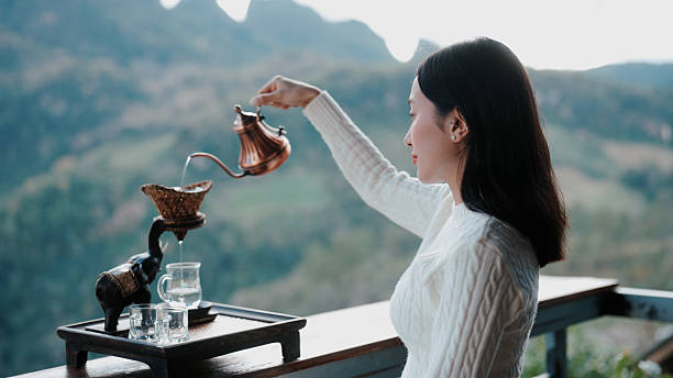 Slowly pouring hot water into a teapot, surrounded by a peaceful mountain view