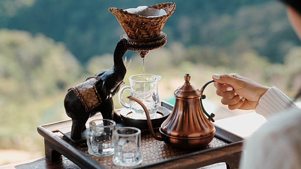 Slowly pouring hot water into a teapot, surrounded by a peaceful mountain view