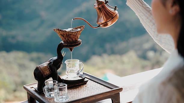 Slowly pouring hot water into a teapot, surrounded by a peaceful mountain view