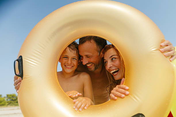 Photo of a young family with one boy, posing for a family photo while on a beach vacation