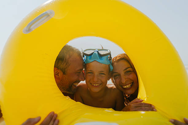 Photo of a young family with one boy, posing for a family photo while on a beach vacation
