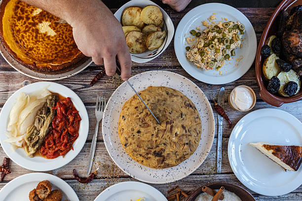istock Person cutting spanish omelet on rustic table surrounded by food 2253908794