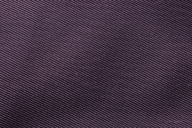 Macro image showing the fine weave and smooth texture of dark purple synthetic fabric material.