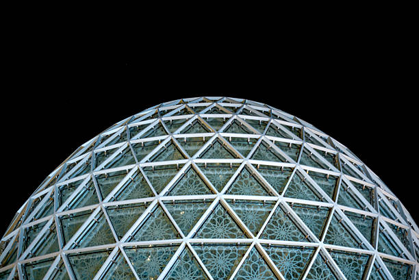 Night view of the blue-lit spherical guest entrance at Sheikh Zayed Grand Mosque, Abu Dhabi, surrounded by landscaped gardens and warm lighting, creating a calm and striking atmosphere.