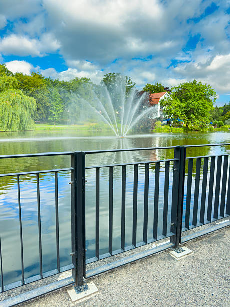 istock A beautifully tranquil park landscape featuring stunning fountain reflections on the serene still water, elegantly surrounded by lush, vibrant trees and a breathtakingly scenic sky above 2253919910