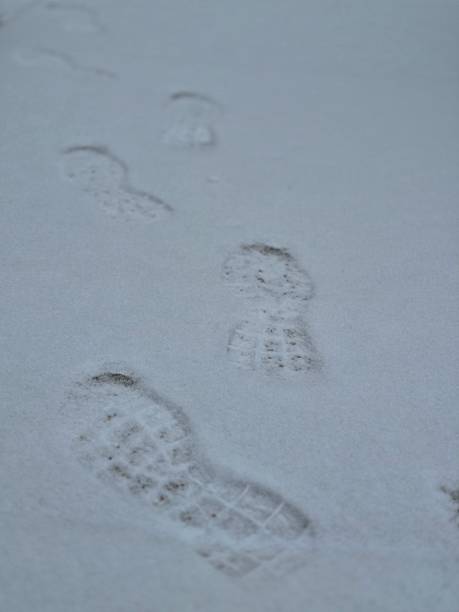 Close-up of snow texture on a ski slope with skis and shoes imprints with a sun spotlight effect