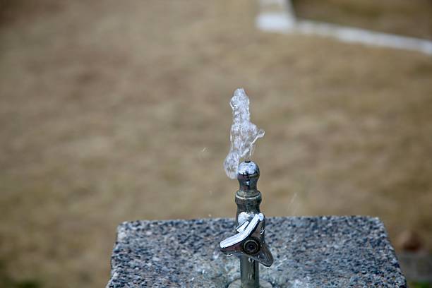 Clear water splashes from a metal public drinking fountain in a Japanese park.The image captures the refreshing motion and detail of flowing water.