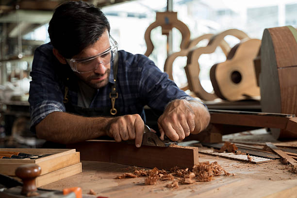 istock Carpenter Using Hand Plane in Wood Shop, Craftsman Shaping Timber with Tools and Sawdust 2253924699