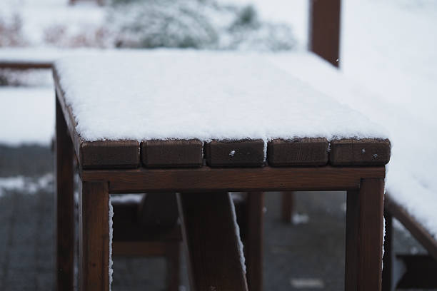 A thick layer of snow blankets a wooden table outside during winter.