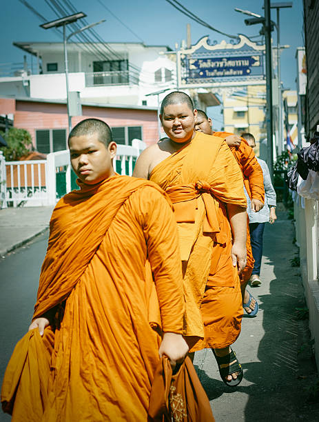 Young asian boy monk wearing traditional orange robe looking forward