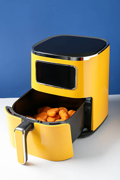 istock Air fryer with chicken nuggets on white table against blue background 2253934075