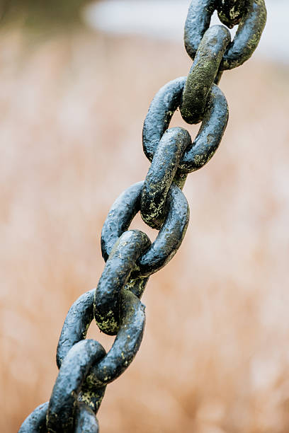 Old iron anchor chain. Rusty chain links defocused diagonally. Simple background.
