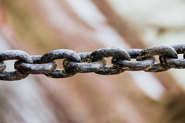 Old iron anchor chain. Rusty chain links defocused diagonally. Simple background.