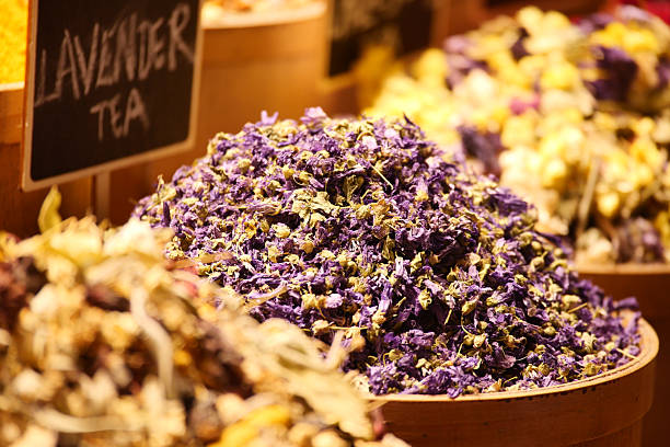 Colorful piles of dried lavender tea in wooden containers.