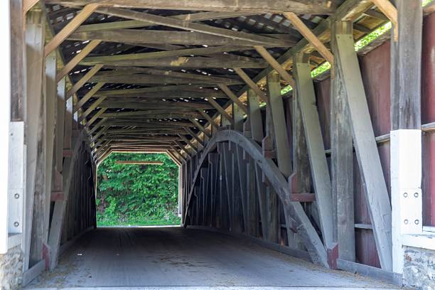 istock Wooden Covered Bridge With Symmetry and Sunlight Illuminating the Interior Structure 2253936335