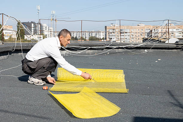 istock Construction worker cuts the yellow reinforcing mesh into two pieces with the utility knife on the roof of a house. 2253937092