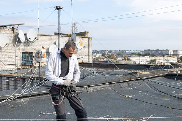 istock Construction worker puts on a safety harness on the roof of a building while working at height. 2253937370