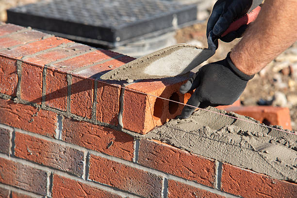 istock Close-up of skilled bricklayer working on construction site laying red bricks for wall construction while 2253937386