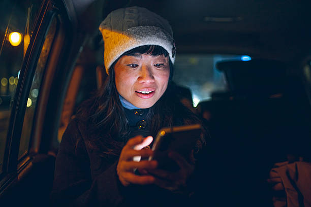 istock Smiling Woman Using Smartphone in Car at Night 2253938138