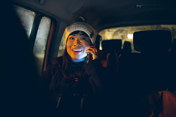 A smiling woman talks on her smartphone while sitting in a car at night